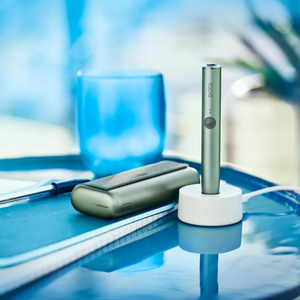 A Jade Green IQOS ILUMA PRIME Holder in a charging station.